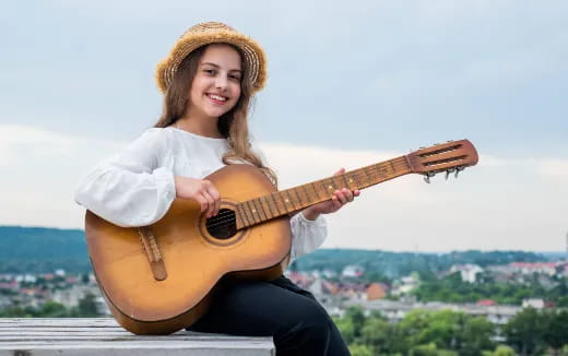 a person sitting on a ledge playing a guitar