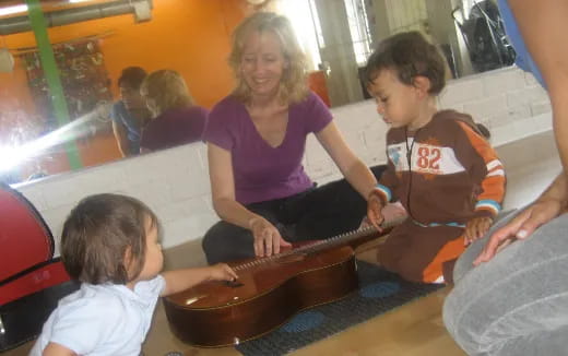 a person and children playing a guitar