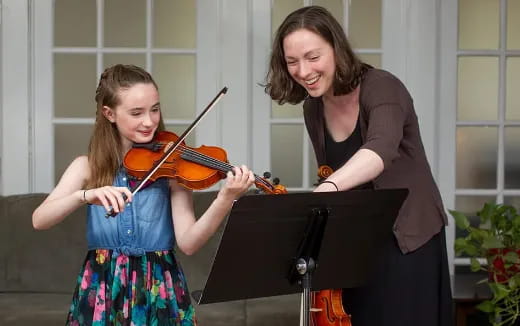a woman playing a violin next to a girl