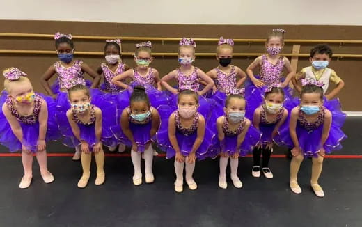 a group of girls in purple and white dresses posing for a photo