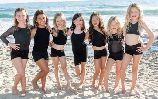 a group of girls in swimsuits on a beach