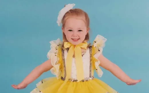 a little girl wearing a yellow dress and a yellow bow