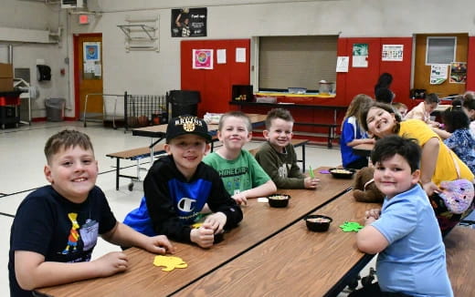 a group of children sitting at a table playing a game
