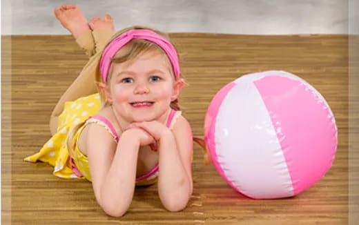 a baby girl holding a pink ball