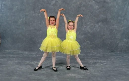 two girls wearing yellow dresses and dancing