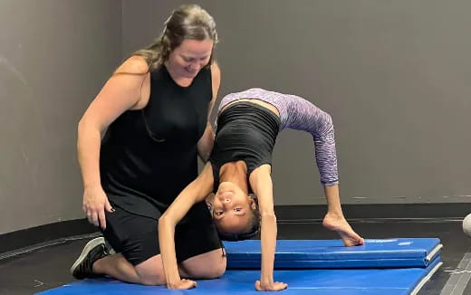 a woman helping a child do push ups