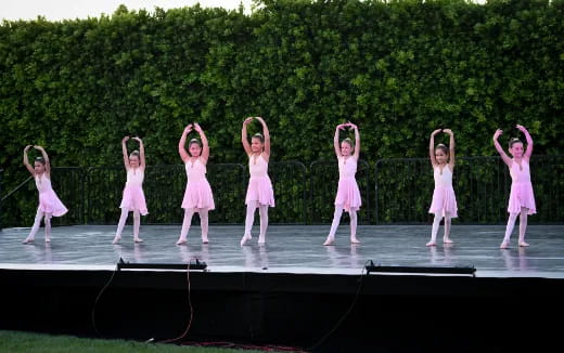 a group of girls in pink dresses on a stage