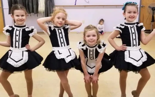 a group of girls wearing black and white dresses and dancing