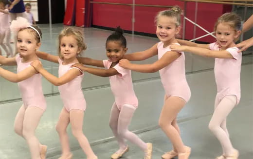 a group of girls in pink ballet outfits
