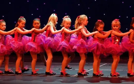a group of girls in pink dancing on a stage
