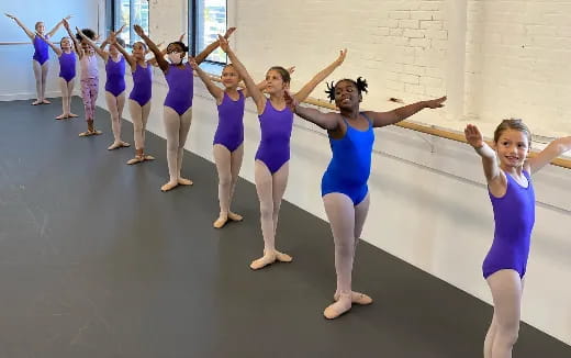 a group of girls in blue and purple dresses dancing on a concrete floor