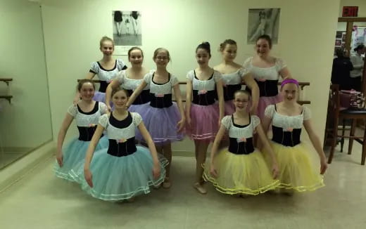 a group of girls in dresses and skirts posing for a photo