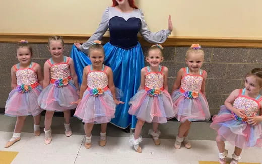 a person standing with a group of girls in dresses