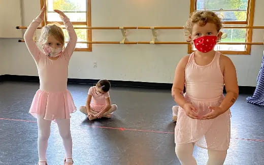 a group of girls wearing pink dresses and holding a rope