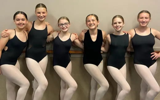 a group of women in black leotards posing for a photo