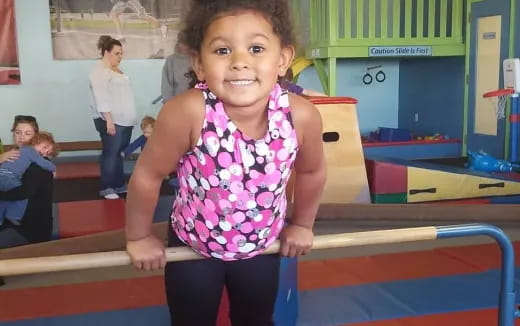 a young girl standing on a blue mat in a gym