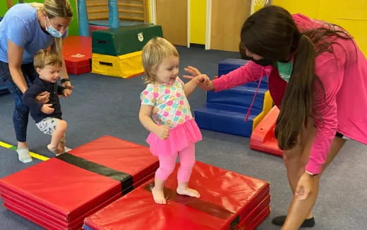 a person and children playing on a mat in a room with colorful toys