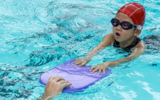 a baby in a pool with a dolphin