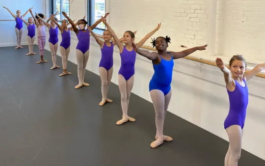 a group of girls in blue leotards dancing in a room