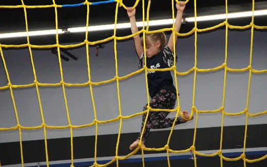 a child climbing a yellow and black net