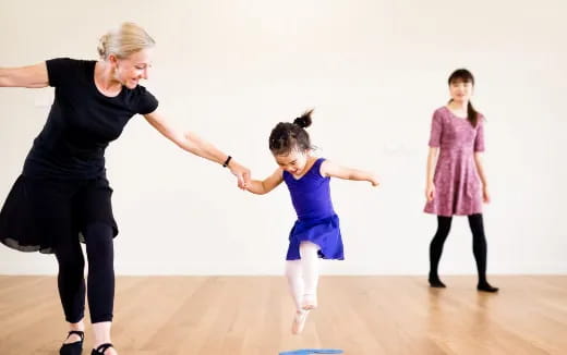 a person and a group of children dancing on a wood floor