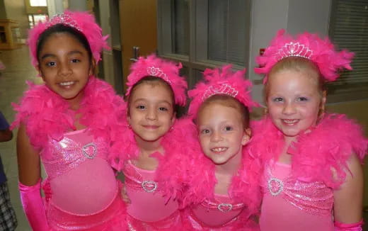a group of girls wearing pink dresses