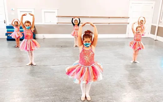 a group of girls wearing dresses and dancing on a stage