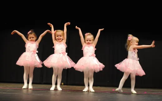 a group of girls in dresses on a stage