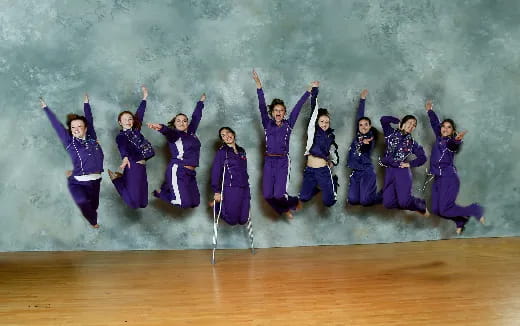 a group of people in purple jumpsuits jumping in the air
