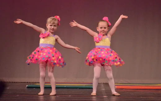 two girls wearing colorful dresses and dancing