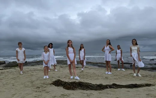a group of women in white dresses on a beach