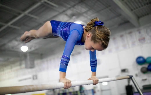 a person in a blue leotard doing gymnastics