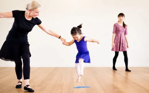 a person and a group of children dancing on a wood floor