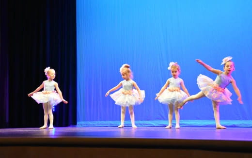 a group of girls in ballet outfits on a stage