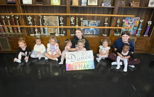 a group of children sitting on the floor holding a sign