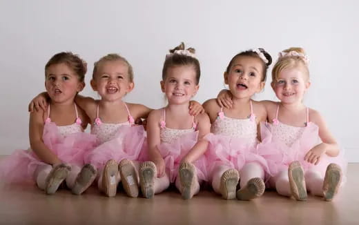 a group of young girls in pink dresses