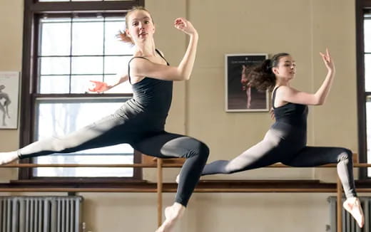 two women jumping on a railing