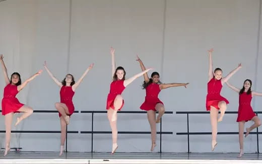 a group of women in red dresses jumping on a stage