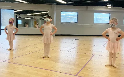 a group of girls wearing white dresses and masks on a stage