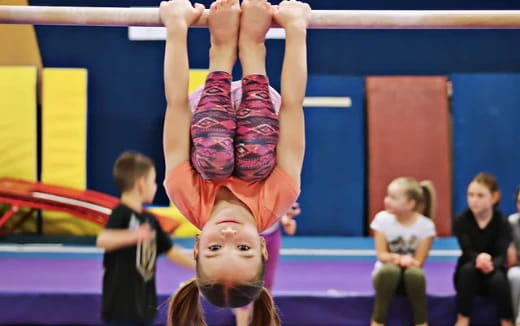 a person doing a handstand on a mat in front of a group of people