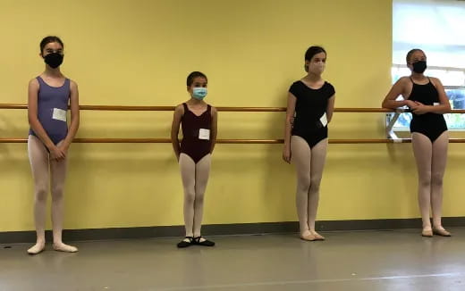 a group of women in leotards standing in front of a yellow wall