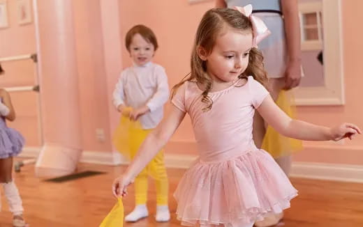 a girl in a pink dress dancing with a boy in a white tutu