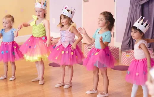 a group of girls wearing dresses and dancing