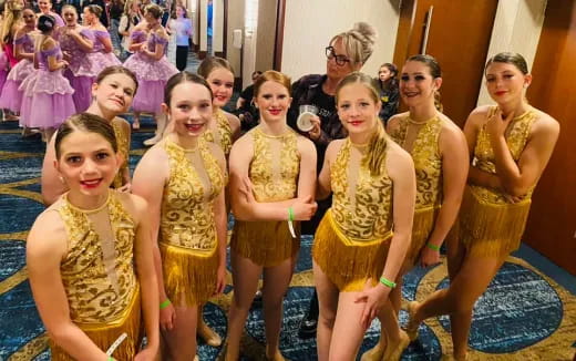 a group of women in gold dresses