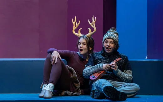 a man and a woman sitting on a stage with their hands up