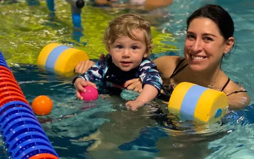 a person and a baby in a pool with balls