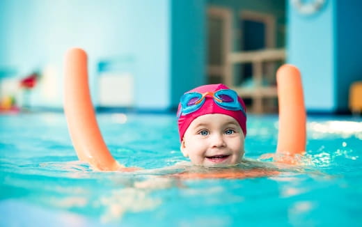 a baby in a pool with a toy in his mouth