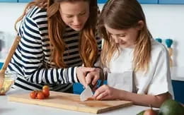 a person and a girl cutting tomatoes