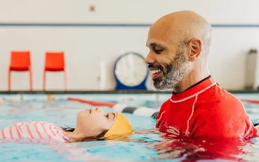 a man in a pool with a baby in it
