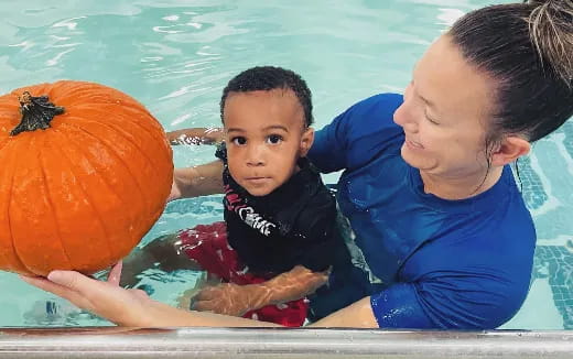 a person and a child in a pool with a ball